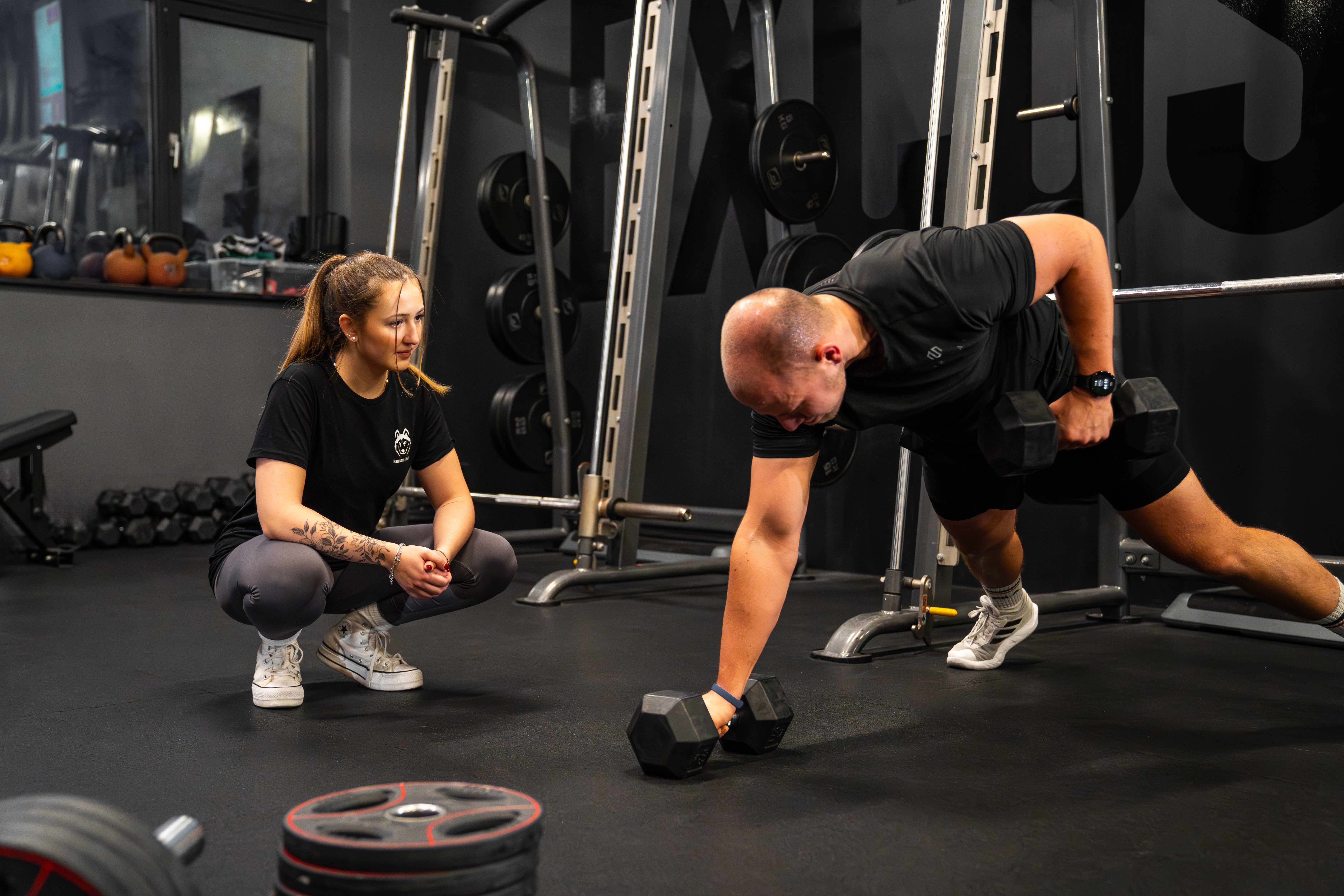 Coach begleitet Mitglied beim Krafttraining mit Hanteln